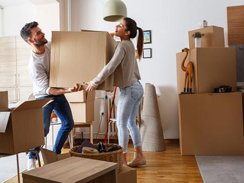 A couple moves a cardboard box while moving.